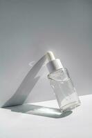 uma branco transparente garrafa com sérum dentro a raios do a Sol. foto