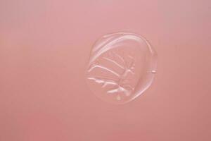 solta do Cosmético transparente gel em uma Rosa fundo. a textura do a sérum, herdeiro gel ou hialurônico booster. foto