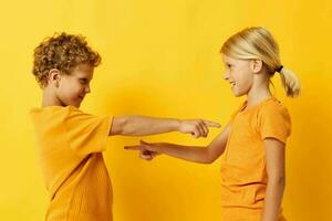 alegre crianças dentro amarelo Camisetas em pé lado de lado infância emoções amarelo fundo inalterado foto