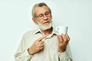 velho homem dentro óculos com uma caneca em uma branco fundo e uma branco camisa foto