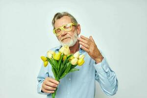 retrato do feliz Senior homem amarelo ramalhete do flores posando isolado fundo foto