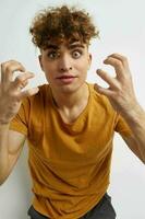 atraente homem dentro amarelo Camisetas gesto mãos emoções luz fundo foto