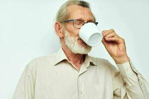 idosos homem bebendo a partir de uma caneca em uma branco fundo e sorridente foto