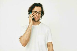 atraente homem dentro uma branco camiseta comunicação de telefone isolado fundo foto