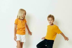 uma Garoto e uma menina dentro amarelo Camisetas estão em pé Próximo para cada de outros em uma luz fundo posando foto