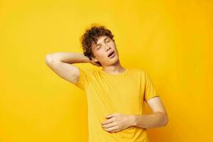 retrato do uma jovem encaracolado homem amarelo camiseta moda mão gestos isolado fundo inalterado foto