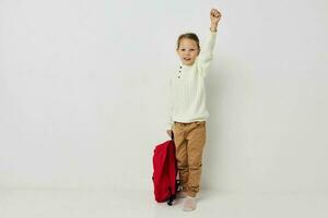 retrato do feliz sorridente criança menina vermelho mochila à moda roupas luz fundo foto