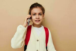 bonita jovem menina estudante mochila telefone dentro mão infância inalterado foto