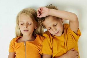 Garoto e menina mentira em uma branco fundo dentro amarelo Camisetas emoções foto