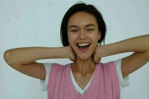 alegre fofa jovem menina dentro uma Rosa colete em uma luz fundo foto