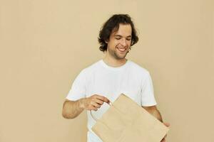 atraente homem dentro uma branco camiseta com papel saco isolado fundo foto