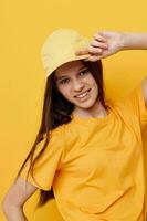 jovem lindo mulher posando dentro uma amarelo camiseta e boné amarelo fundo foto