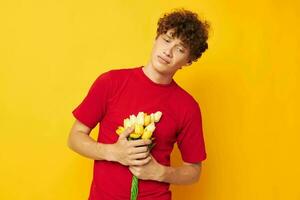 retrato do uma jovem encaracolado homem dentro uma vermelho camiseta uma ramalhete do flores feriado presente monocromático tiro foto