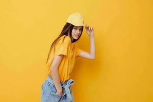 jovem lindo mulher posando dentro uma amarelo camiseta e boné amarelo fundo foto