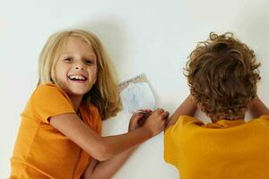 Garoto e menina desenhando dentro cadernos deitado em a chão infância estilo de vida inalterado foto