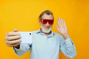 retrato idosos homem azul camisas com óculos leva uma selfie inalterado foto