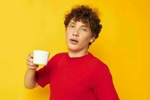 retrato do uma jovem encaracolado homem dentro uma vermelho camiseta com uma branco boné dentro dele mãos isolado fundo inalterado foto