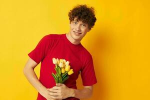 jovem cabelo encaracolado homem dentro uma vermelho camiseta com uma ramalhete do flores estilo de vida inalterado foto