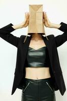atraente mulher dentro uma couro terno Preto Jaqueta com uma saco em dele cabeça isolado fundo foto