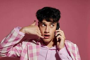 retrato do uma jovem homem com uma telefone dentro mão Rosa blazer moda elegante estilo estilo de vida inalterado foto