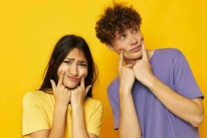 fofa jovem casal casual roupas posando emoções palhaçadas amarelo fundo inalterado foto