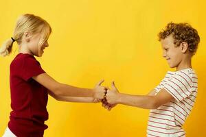 fofa à moda crianças em pé lado de lado posando infância emoções amarelo fundo foto