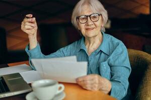 idosos mulher trabalhando dentro frente do computador portátil monitor sentado aposentado mulher conversando inalterado foto