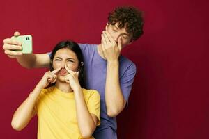 jovem homem e menina dentro colorida Camisetas com uma telefone juventude estilo foto