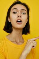 jovem mulher dentro amarelo camiseta posando moda amarelo fundo foto