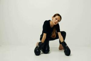 lindo menina dentro boxe luvas em a chão dentro Preto camiseta luz fundo foto