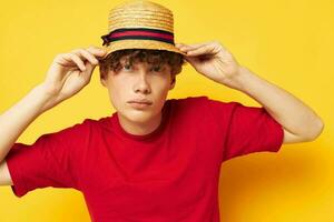 retrato do uma jovem encaracolado homem dentro uma vermelho camiseta com uma moda chapéu estilo de vida inalterado foto