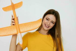 retrato do uma jovem mulher dentro casual roupas, a avião dentro dele mãos isolado fundo foto