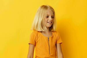 fofa pequeno menina dentro uma amarelo camiseta sorrir posando estúdio cor fundo inalterado foto