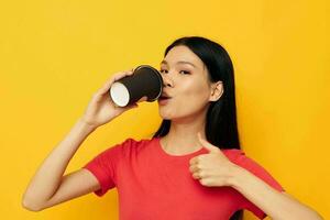 mulher dentro uma vermelho camiseta vidro com uma beber amarelo fundo foto