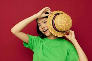 retrato ásia lindo jovem mulher dentro uma verde camiseta gesticulando com dele mãos Diversão vermelho fundo inalterado foto