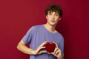 jovem homem coração em forma presente vermelho fundo foto