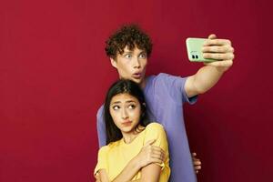 uma jovem casal dentro colorida Camisetas com uma telefone juventude estilo foto