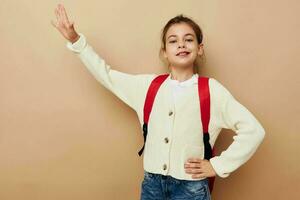 pequeno menina estudante com vermelho mochila posando infância inalterado foto