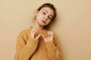 fofa menina dentro suéter posando mão gestos bege fundo foto