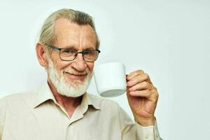 a idosos homem segurando uma caneca em uma branco fundo e sorridente foto