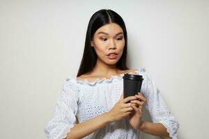 retrato ásia lindo jovem mulher posando com uma descartável vidro do Diversão beber isolado fundo inalterado foto