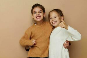 dois engraçado pequeno meninas abraço amizade posando bege fundo foto