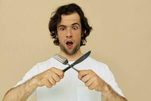 atraente homem emoções faca e garfo utensílios de cozinha isolado fundo foto