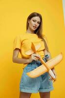 retrato do uma jovem mulher posando amarelo avião dentro a mãos do Diversão estilo de vida inalterado foto