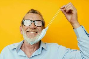 retrato idosos homem com óculos segurança médico mascarar posando amarelo fundo foto