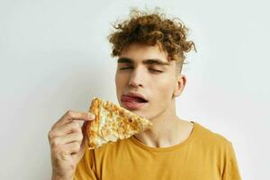 bonito jovem homem dentro uma amarelo camiseta comendo pizza estilo de vida inalterado foto