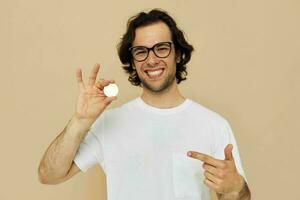 alegre homem dentro uma branco camiseta com bitcoin criptomoeda bege fundo foto