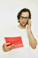 atraente homem dentro uma branco camiseta vermelho bloco de anotações estilo de vida inalterado foto