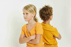 cenário do positivo Garoto e menina dentro amarelo Camisetas em pé lado de lado infância emoções inalterado foto