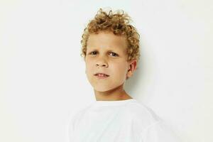 emocional Garoto com encaracolado cabelo dentro uma branco camiseta fechar acima foto